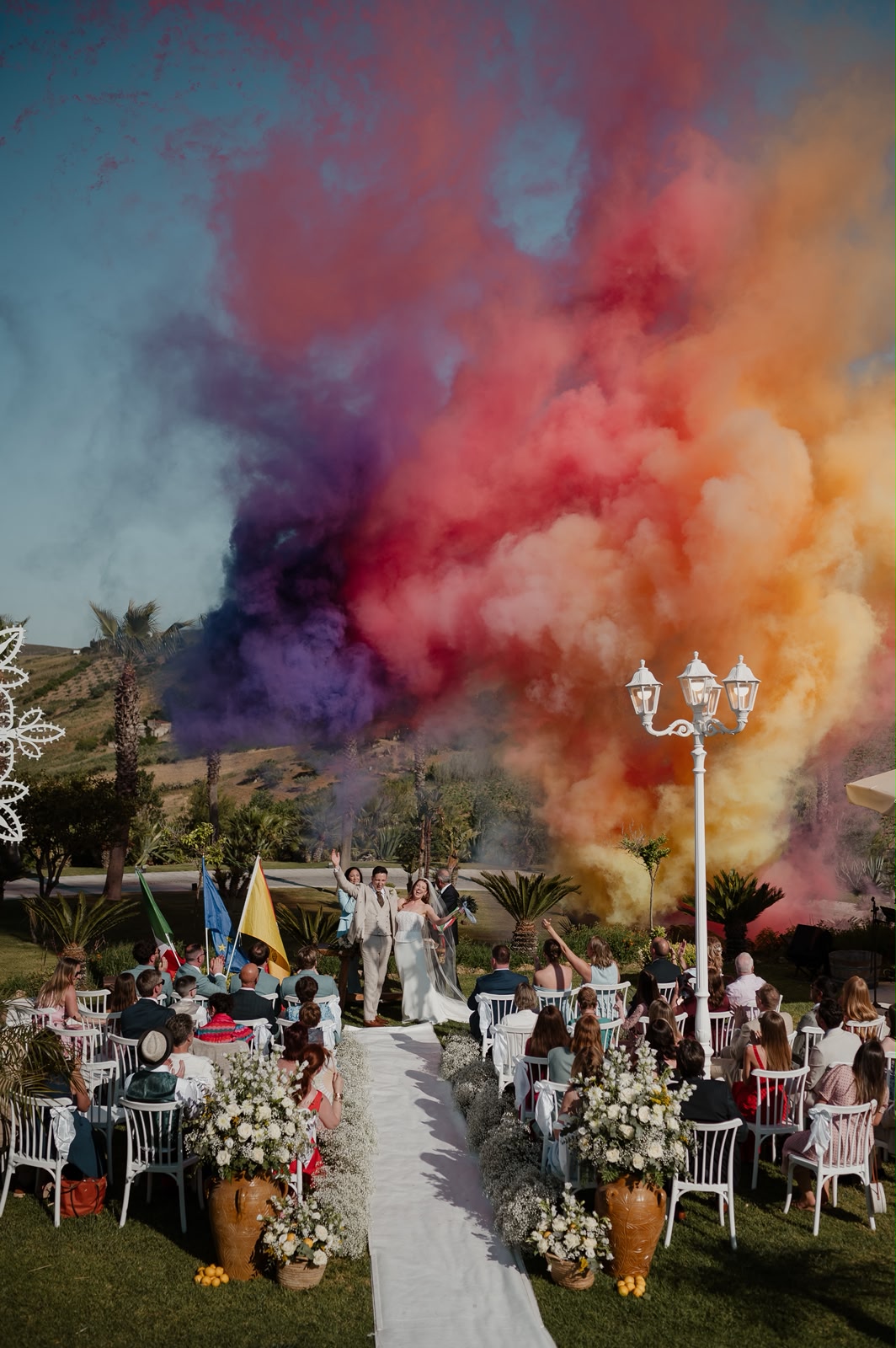 Jessica and Seb celebrating along the aisle amid a cloud of coloured smoke after their ceremony