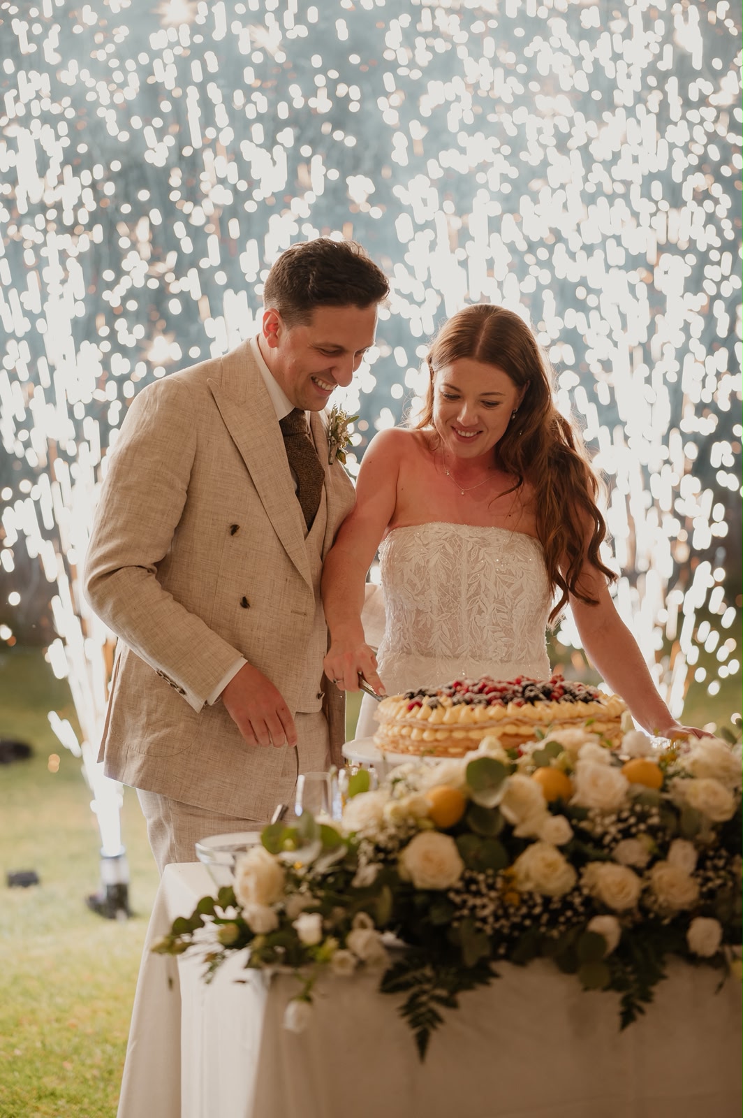 Wedding cake lit with sparklers at an evening reception