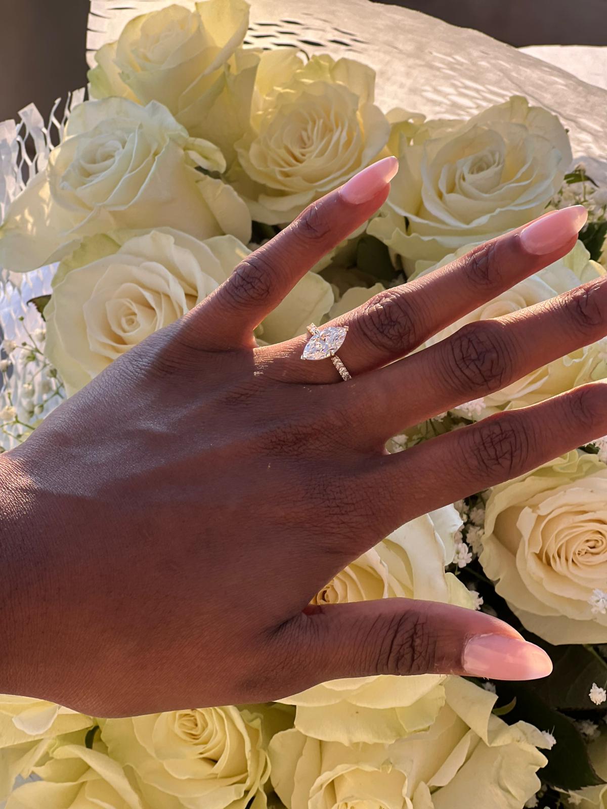 Close-up of an engagement ring above white roses