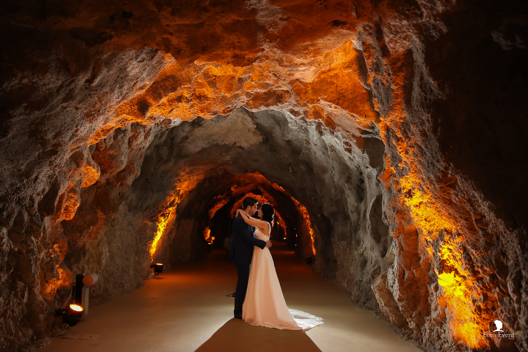 Bride and groom sharing a kiss beside a baroque stone fountain in a sunlit Sicilian plaza