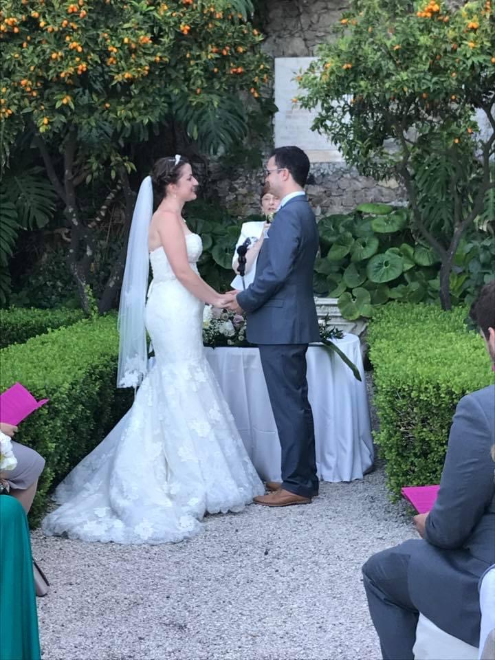 Bride and groom exchanging vows before their officiant at an outdoor garden wedding ceremony in Sicily