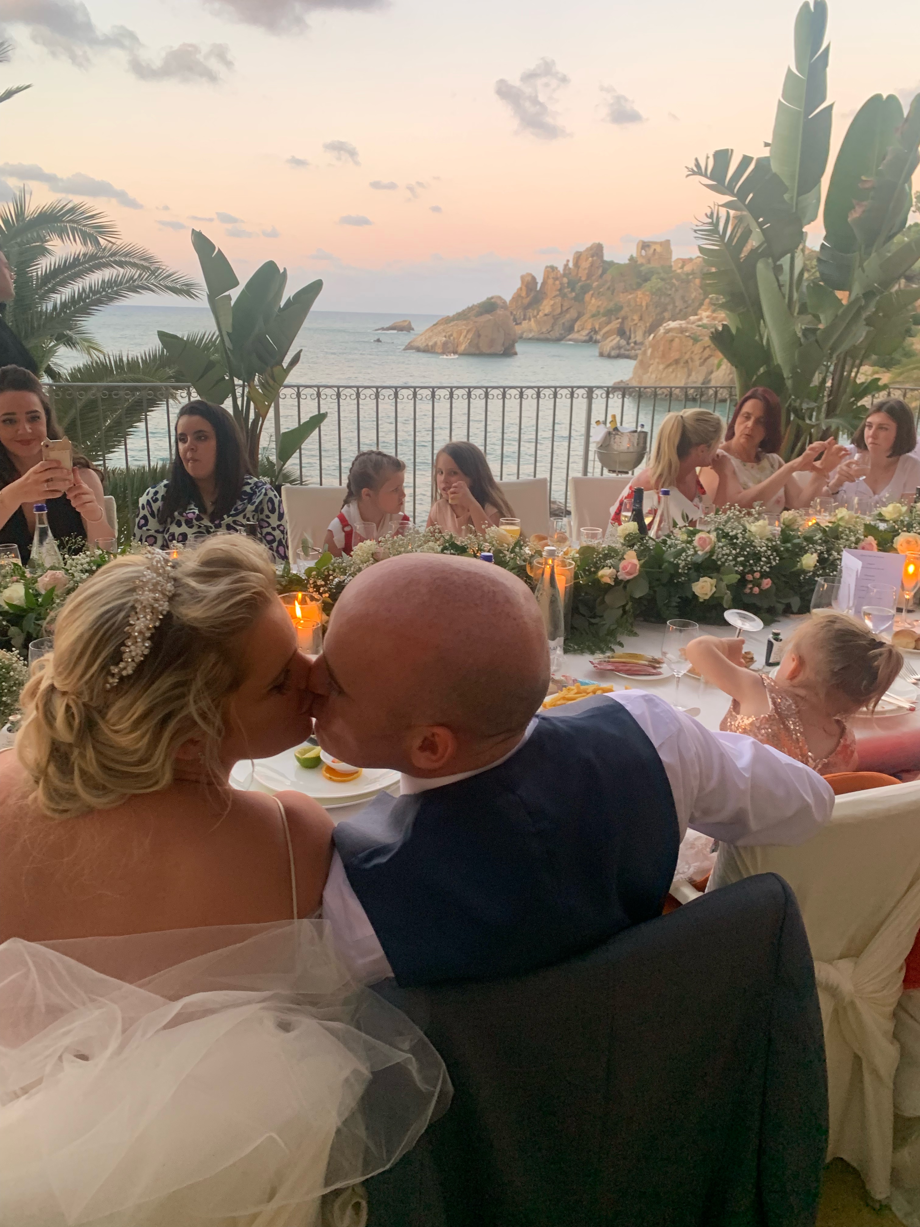 Couple kissing at a candlelit terrace wedding dinner