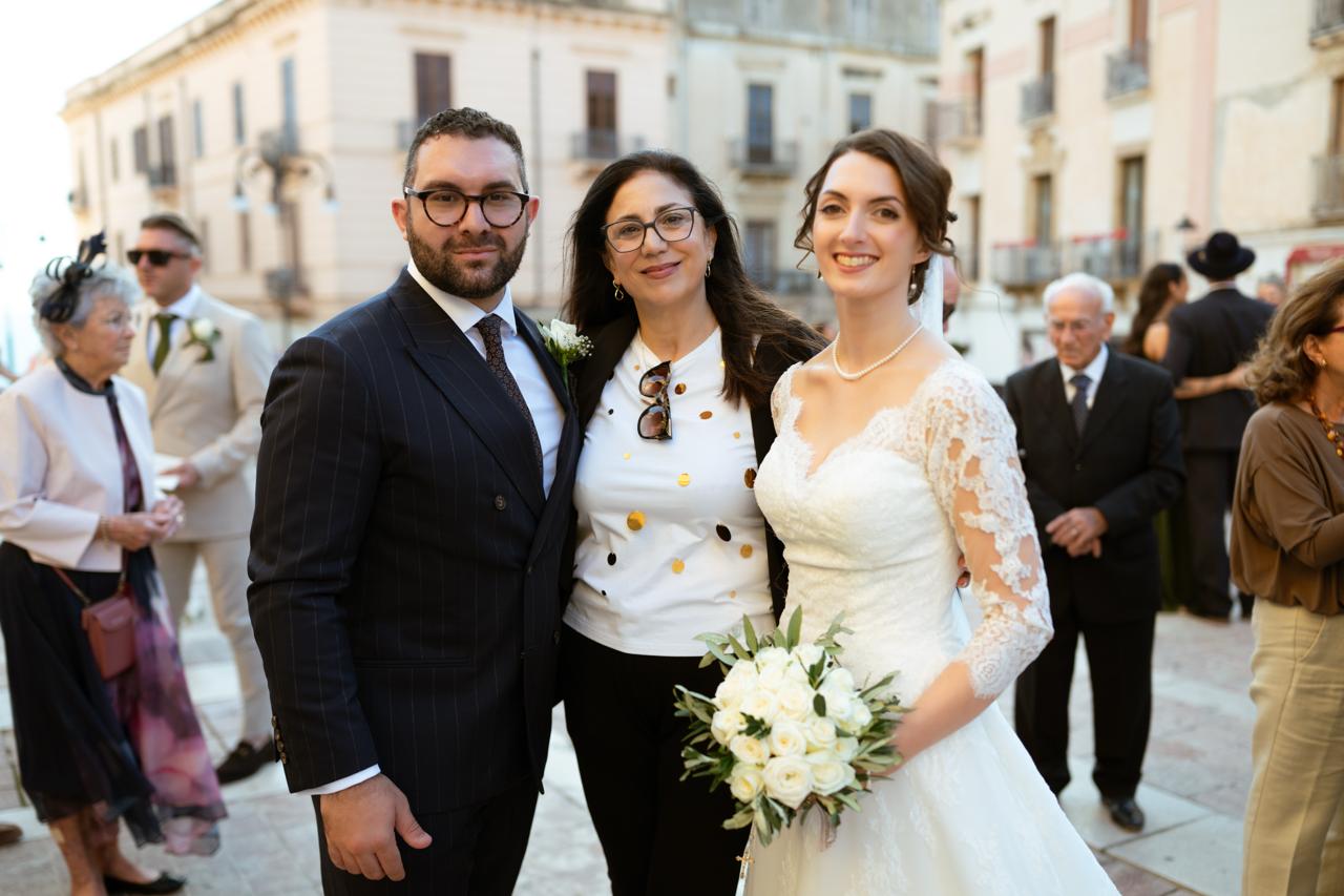 Isabella and Billy with a guest in the square after the ceremony, Isabella holding a white bouquet
