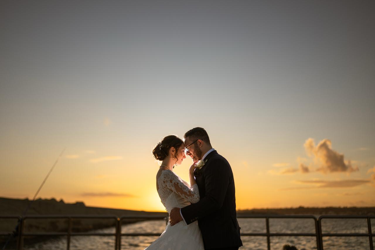 Bride and groom silhouetted against a golden Sicilian sunset