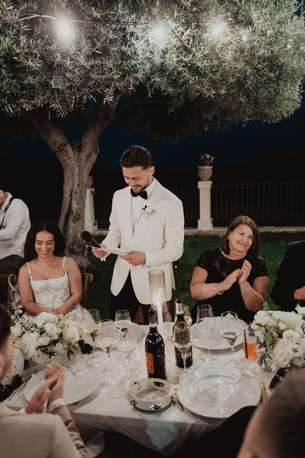 Rian giving his speech beneath an olive tree as Lidia smiles