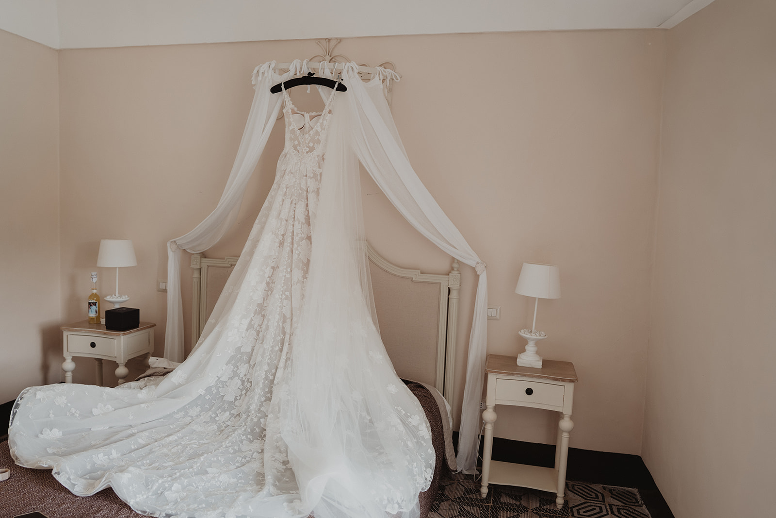 Lidia’s lace wedding dress and veil hanging above the bed at Borgo del Carato