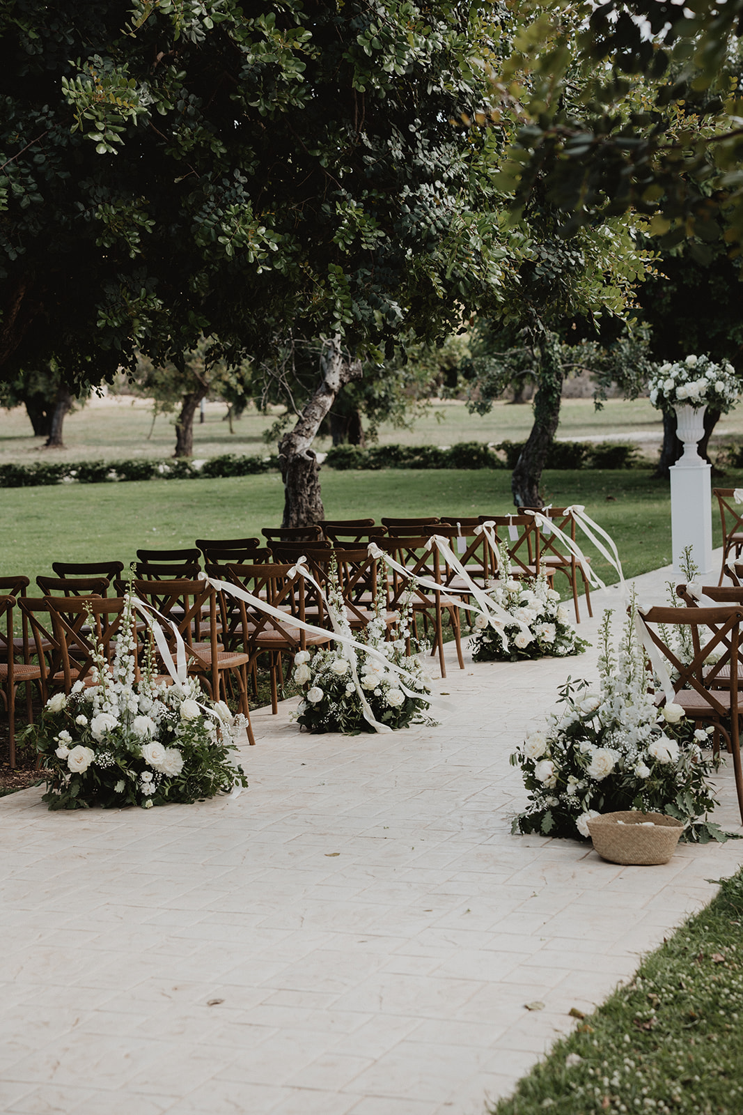 The ceremony aisle at Borgo del Carato lined with white florals and ribbons beneath the trees