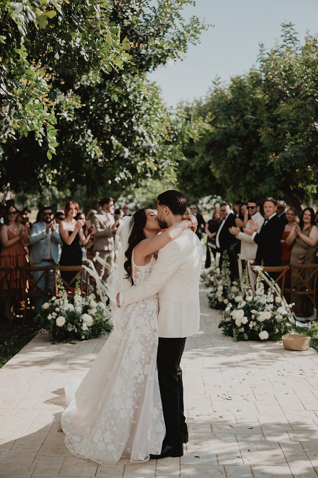 Lidia and Rian kissing in the aisle as their guests applaud