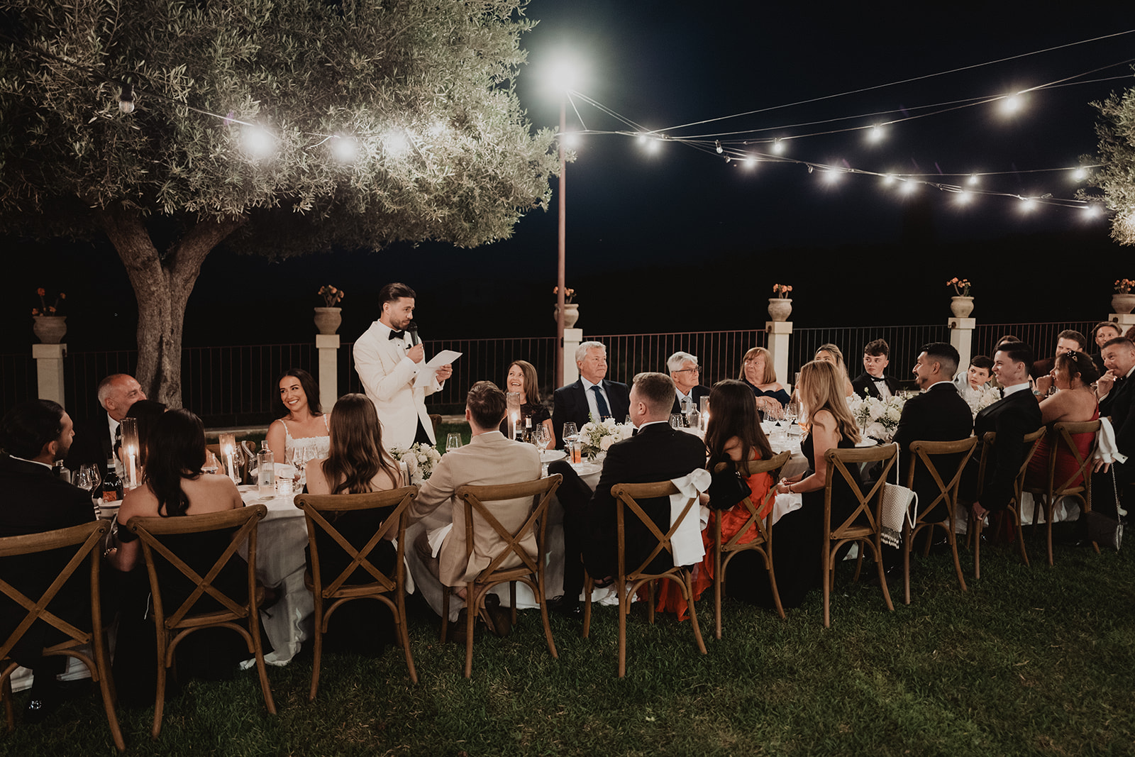 A speech at the table after dark beneath strings of lights