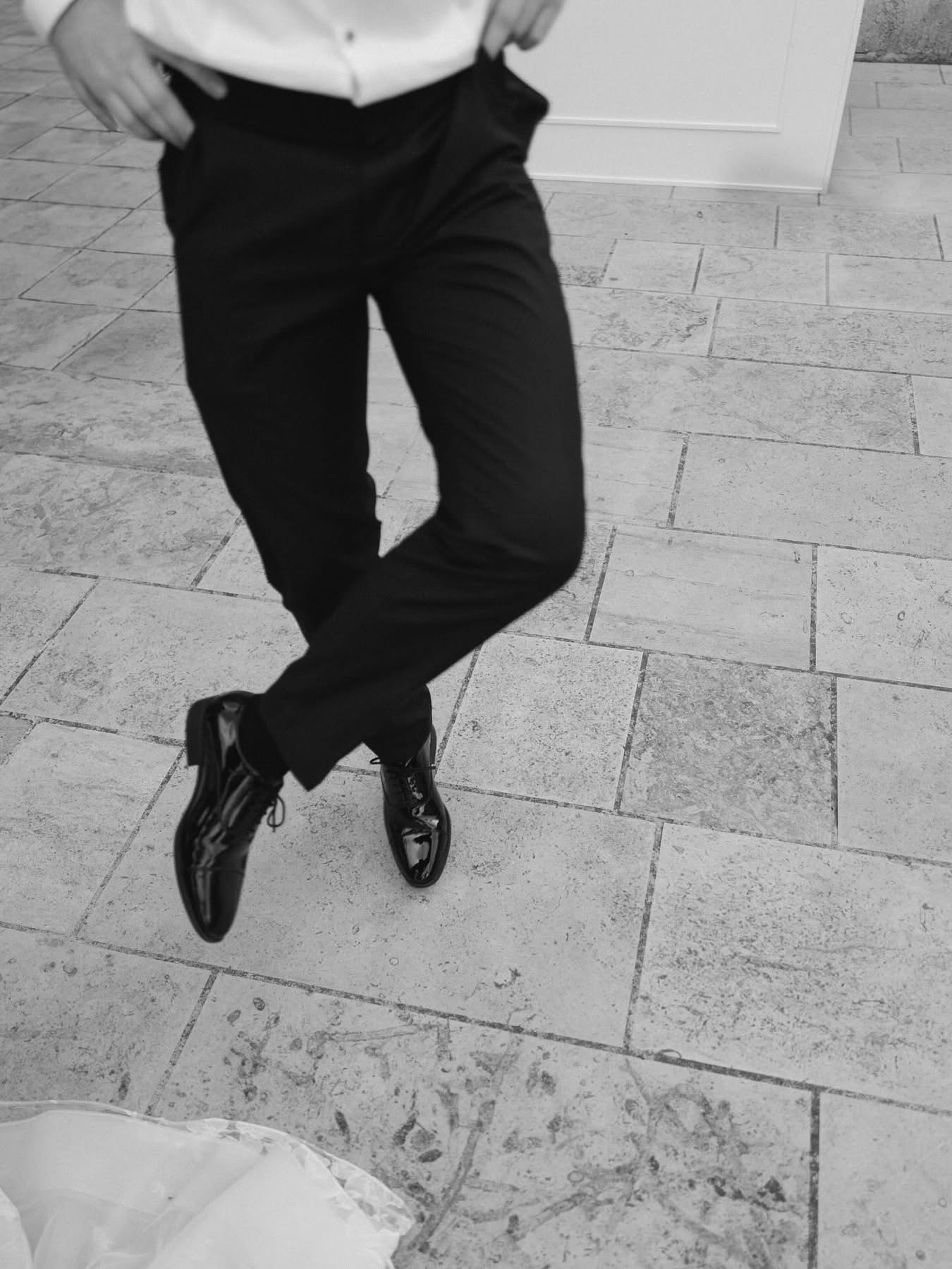 A black-and-white close-up of dancing feet in patent shoes