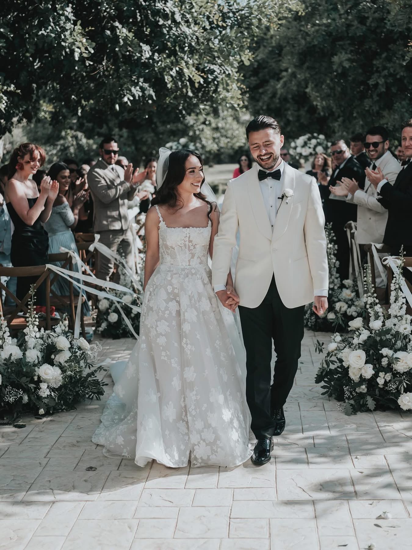 Lidia and Rian smiling as they leave the aisle as newlyweds