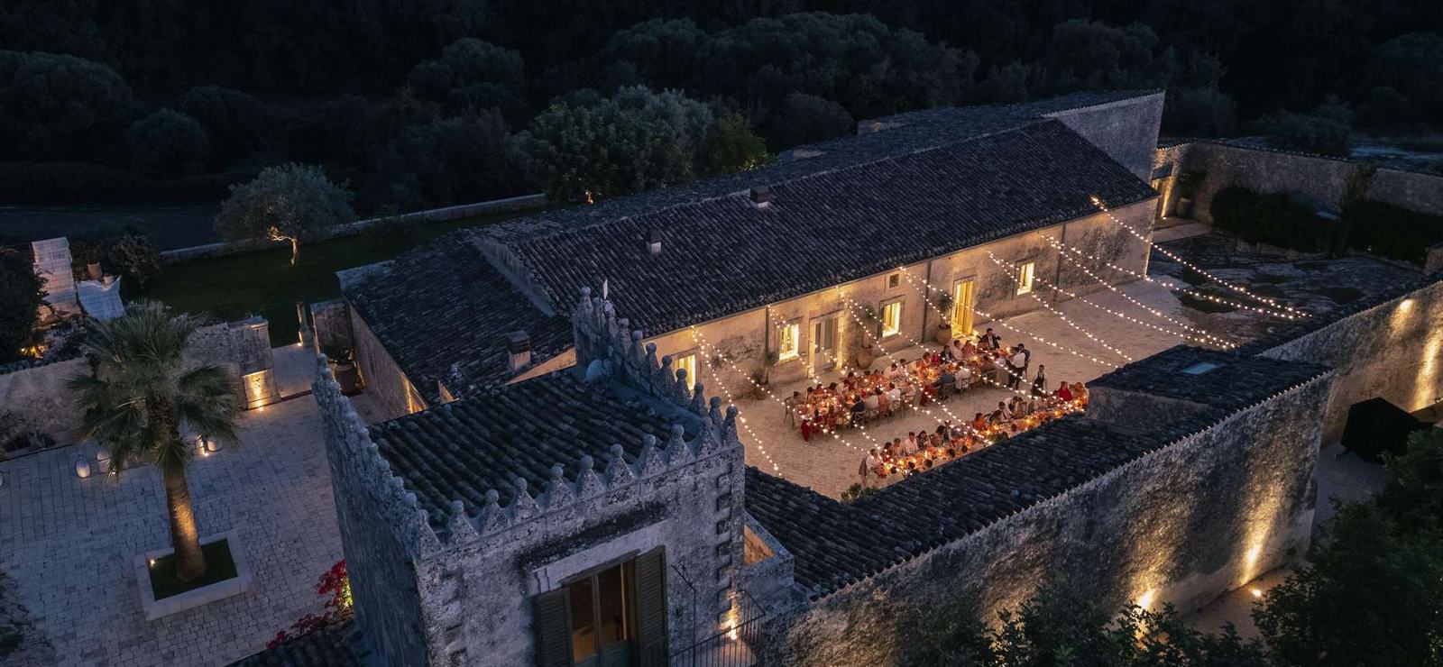 Dimora delle Balze from the air at dusk, with a wedding dinner laid out in the courtyard of the 19th-century estate in the Val di Noto