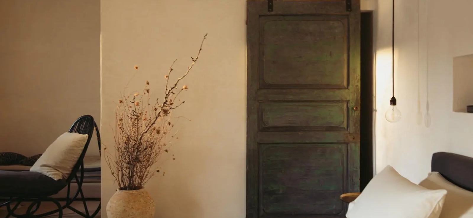 A guest room at Dimora delle Balze with simple, natural furnishings and an old wooden door