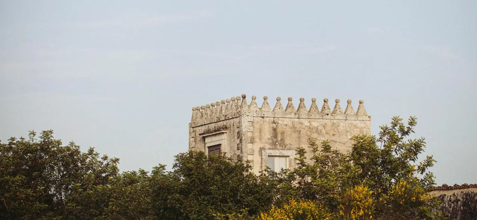 The tower of Dimora delle Balze rising above the trees at sunset, a 19th-century estate near Noto in Sicily