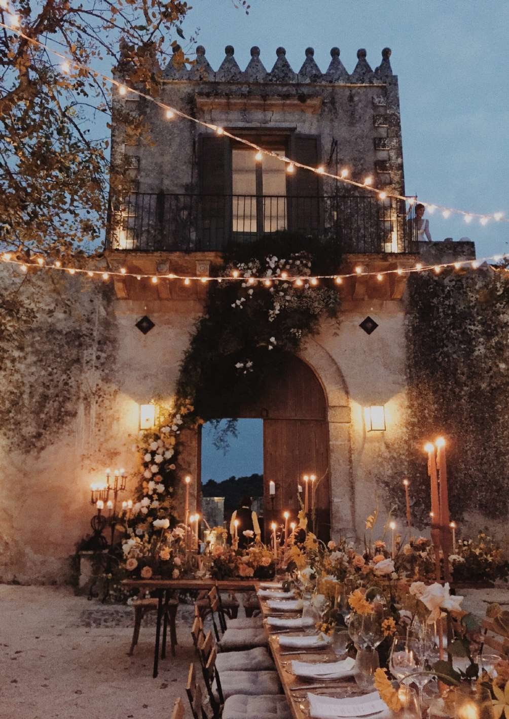 Candlelit wedding dinner beneath string lights at the foot of the estate’s tower at Dimora delle Balze