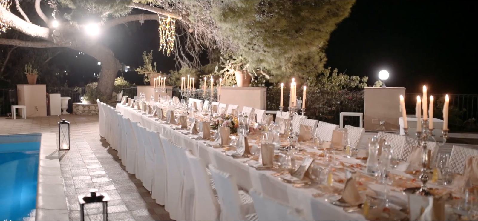 A long candlelit wedding table beside the pool in the gardens of the Excelsior Palace, Taormina