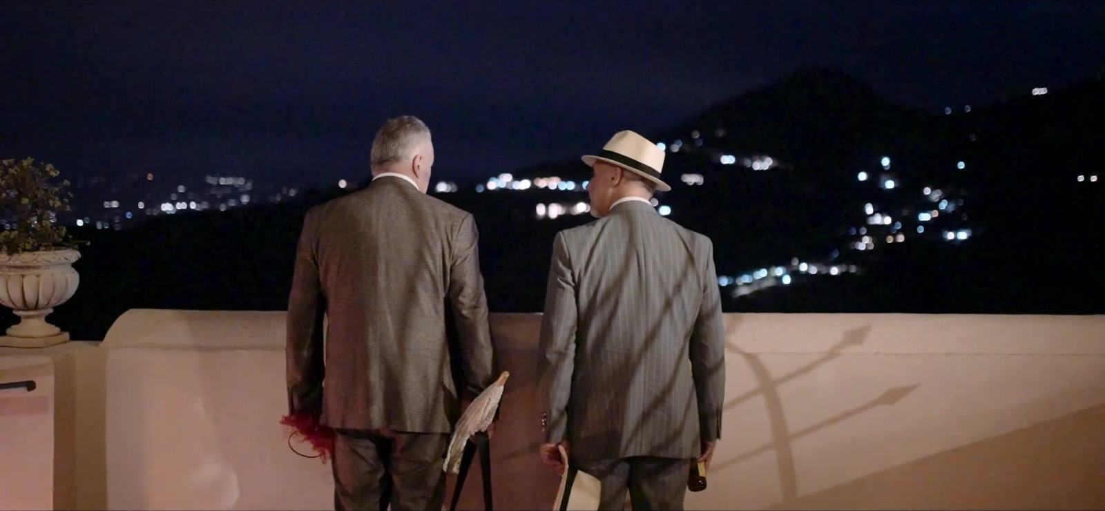 Wedding guests on a terrace at the Excelsior Palace looking out over the lights of the Taormina coast at night
