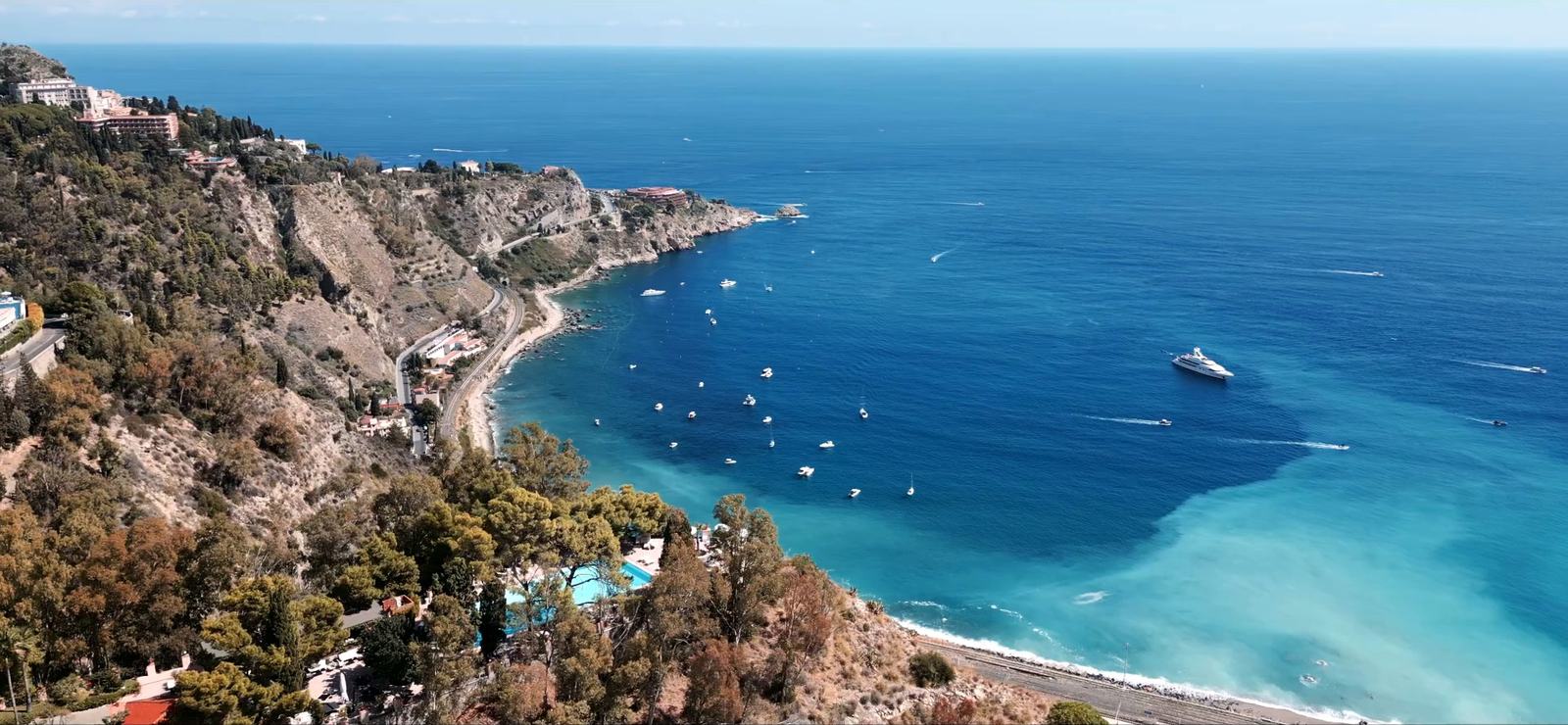 The Ionian coast around Taormina seen from the air, with boats on the turquoise sea